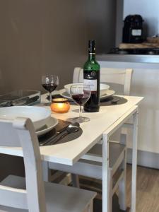 a white table with a bottle of wine and glasses at Les Etoiles studio in Durbuy +4 photos