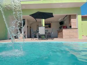 a pool with an umbrella and a table and chairs at Espaço Alvorada com Banheira ,agendamento das atividades, café da manhã no centro in Brotas