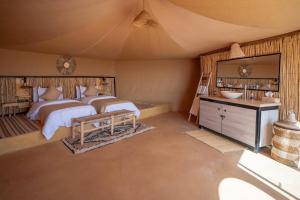 a large bedroom with two beds and a sink at Kalimba Luxury Desert Camp in Merzouga
