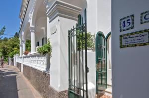 a white building with a green gate on a street at Villa Mariuccia Capri in Capri