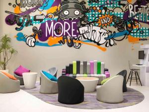 雅加达Ibis Styles Jakarta Mangga Dua Square的一间房间,配有椅子和涂有涂鸦的墙壁