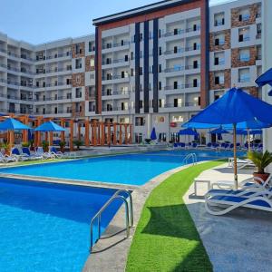 a swimming pool with chairs and umbrellas in front of a building at Tiba Golden beach resort hurghada down town in Hurghada