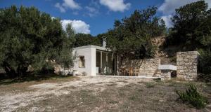 a white house with a stone wall and trees at Paleopoli Cave House in Kythira