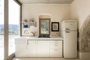 a white kitchen with a refrigerator and a window at Paleopoli Cave House in Kythira +15 photos
