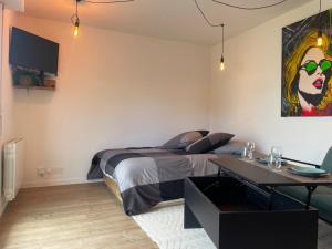 a bedroom with a bed and a desk and a table at Unique Urban Art Studio in Lisieux