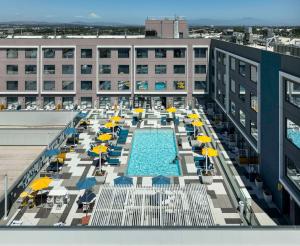 a pool on the roof of a building with chairs and umbrellas at Hilton Buena Park Anaheim in Buena Park