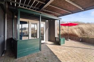 a house with a green porch with a red umbrella at Co's Duyne - Beautiful studio near the dunes of Callantsoog in Callantsoog