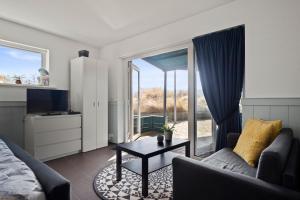 a living room with a couch and a table and a window at Co's Duyne - Beautiful studio near the dunes of Callantsoog in Callantsoog +16 photos