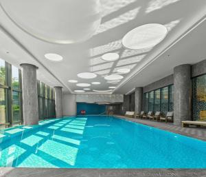 a large swimming pool in a building with a ceiling at Doubletree By Hilton Yantai Golden Coast Hotel & Suites in Yantai
