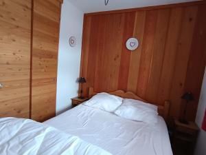 - une chambre avec un lit blanc et des murs en bois dans l'établissement Appartement cosy à 30m des pistes, plein sud avec terrasse - FR-1-445-145, à Montgenèvre
