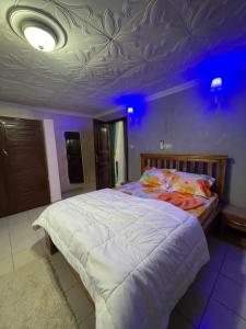 a bedroom with a large bed with a purple ceiling at Black Diamond Appartements in Kribi