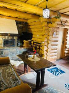 a living room with a table and a stone fireplace at садиба "У Чубчика" in Yaremche