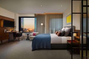 墨尔本Next Hotel Melbourne, Curio Collection by Hilton的一间带床和书桌的酒店房间