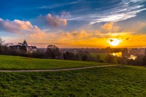 a sunset over a field with a building in the background at The Petersham in Richmond upon Thames