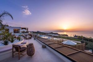a resort with a view of the ocean at sunset at Isla Brown Chania Resort, Curio Collection by Hilton in Stavros