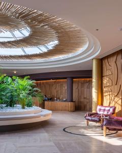 a lobby with a ceiling with a chair and a couch at Isla Brown Chania Resort, Curio Collection by Hilton in Stavros