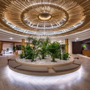 a large lobby with a large chandelier and plants at Isla Brown Chania Resort, Curio Collection by Hilton in Stavros