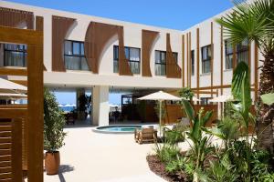 a building with a courtyard with chairs and umbrellas at Isla Brown Chania Resort, Curio Collection by Hilton in Stavros