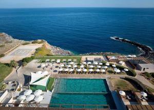 an aerial view of a resort with a swimming pool and the ocean at Isla Brown Chania Resort, Curio Collection by Hilton in Stavros