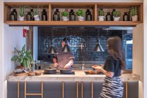 a man and a woman preparing food in a kitchen at Isla Brown Chania Resort, Curio Collection by Hilton in Stavros