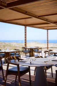 an empty restaurant with tables and chairs and the ocean at Isla Brown Chania Resort, Curio Collection by Hilton in Stavros