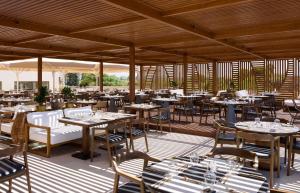a restaurant with tables and chairs on a patio at Isla Brown Chania Resort, Curio Collection by Hilton in Stavros
