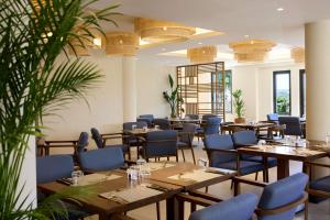 a restaurant with wooden tables and blue chairs at Isla Brown Chania Resort, Curio Collection by Hilton in Stavros