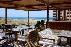a restaurant with tables and chairs and a view of the ocean at Isla Brown Chania Resort, Curio Collection by Hilton in Stavros