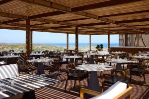 a restaurant with tables and chairs on a deck at Isla Brown Chania Resort, Curio Collection by Hilton in Stavros