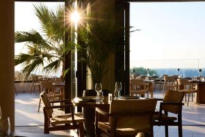 a restaurant with a table and chairs with a view of the ocean at Isla Brown Chania Resort, Curio Collection by Hilton in Stavros
