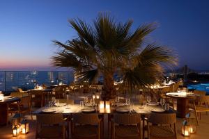 a restaurant with tables and a palm tree on a roof at Isla Brown Chania Resort, Curio Collection by Hilton in Stavros