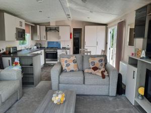 a living room with a couch and a kitchen at Sunset retreat lodge with large wrap around decking in Newquay
