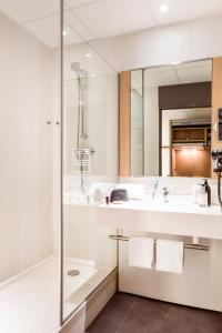 ein weißes Bad mit einer Dusche und einem Waschbecken in der Unterkunft Aparthotel Adagio Paris Malakoff Chatillon in Malakoff
