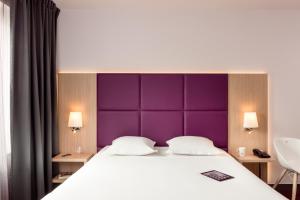 a bedroom with a large bed with a purple headboard at Aparthotel Adagio Paris Malakoff Chatillon in Malakoff