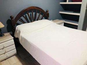 a bedroom with a white bed with a wooden headboard at La quinta de los peques in Los Toldos
