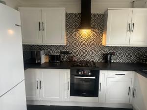 a kitchen with white cabinets and a stove top oven at Tranquil one bed flat in Newquay