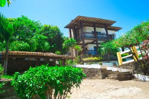 a building in the middle of a garden with trees at Casa em Ilheus-Olivença in Olivença