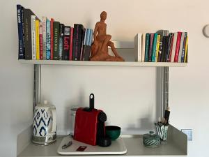 a shelf with books and a coffee maker on a desk at Shoreditch Rooftop Suites in London