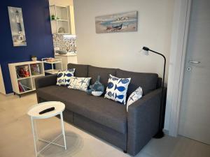 a living room with a gray couch and a stool at Casa al mare Teresa in Porto SantʼElpidio