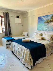 a bedroom with two beds and a painting on the wall at Flat dos Anjos in Arraial do Cabo
