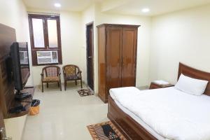 a bedroom with a bed and a tv and chairs at Vibha Raj Grand in Kānpur