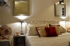 una camera da letto con un letto con lenzuola bianche e cuscini rossi di Marè Rooms Bari old town center a Bari