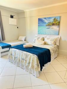 a bedroom with two beds and a painting on the wall at Flat dos Anjos in Arraial do Cabo
