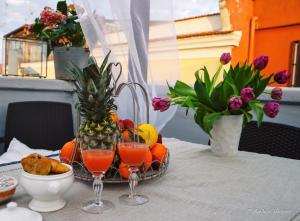 a table with two glasses of juice and a basket of fruit at Marè Rooms Bari old town center in Bari