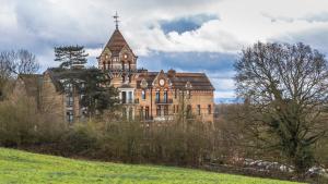 a large building with a tower on top of a field at The Petersham in Richmond upon Thames