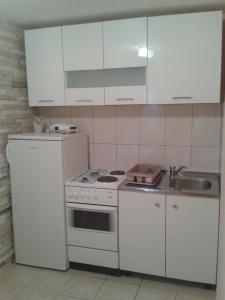 a kitchen with white cabinets and a stove and a sink at Apartments and Rooms Jasna in Hvar