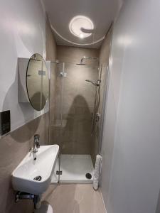 a bathroom with a shower and a sink and a mirror at Shoreditch Rooftop Suites in London +34 photos