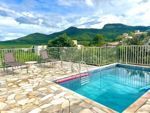 a swimming pool with two chairs and a fence at Casa Bela Vista in Capitólio