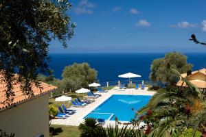 a swimming pool with chairs and umbrellas and the ocean at Pantheon Villas in Agios Nikitas