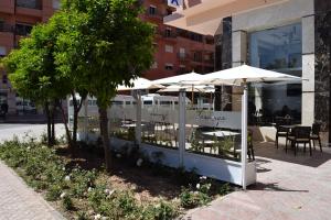 a restaurant with tables and umbrellas in front of a building at H&ocirc;tel Teranga & Spa in Marrakech